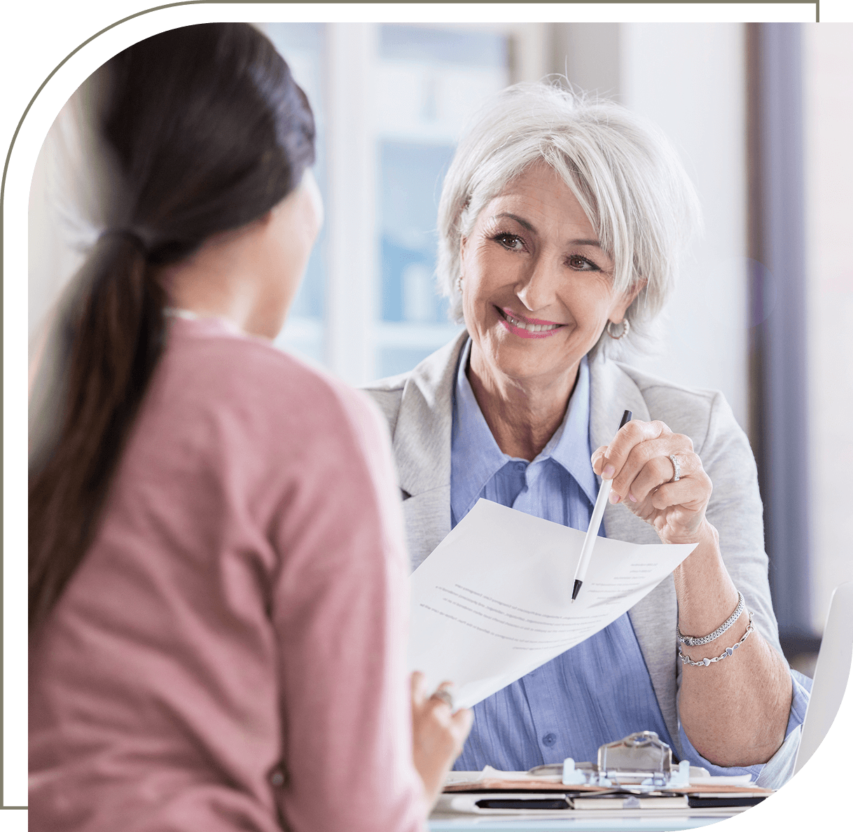 Two women discussing paperwork in an office.