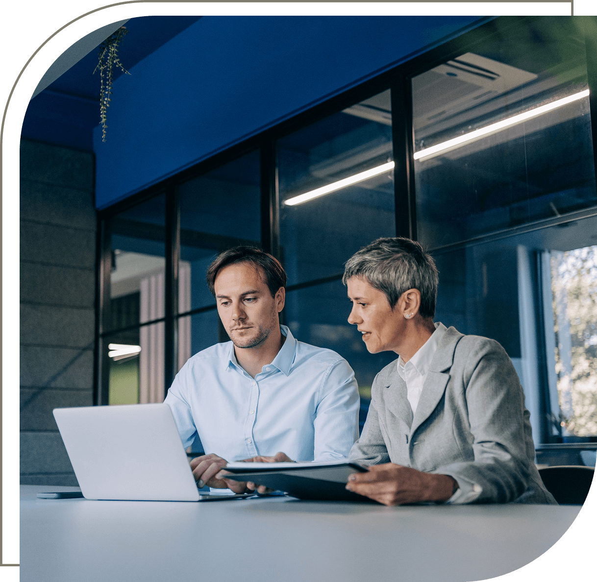 Two people discussing work at laptop.