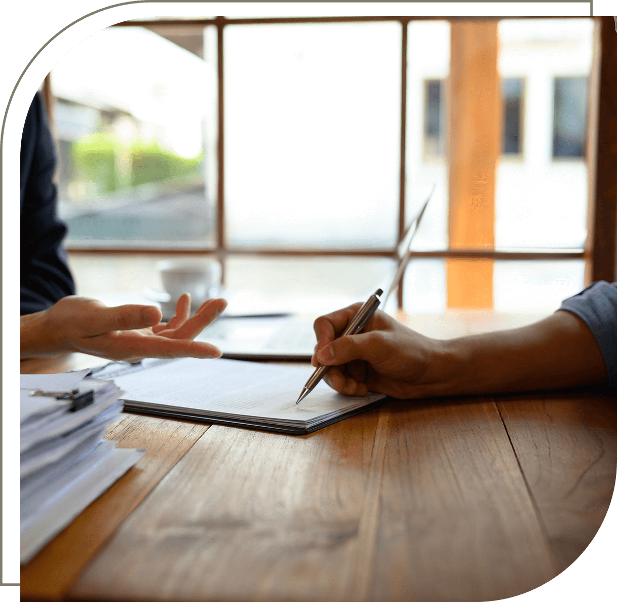 Two people discussing at a wooden table.