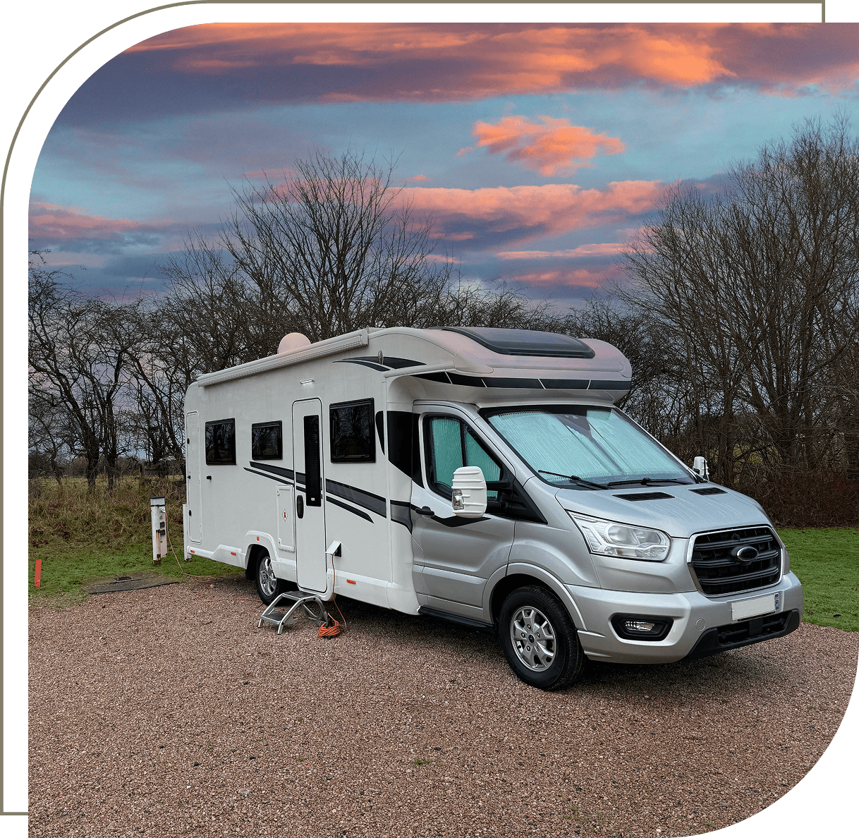 Camper van parked under colorful sunset sky.